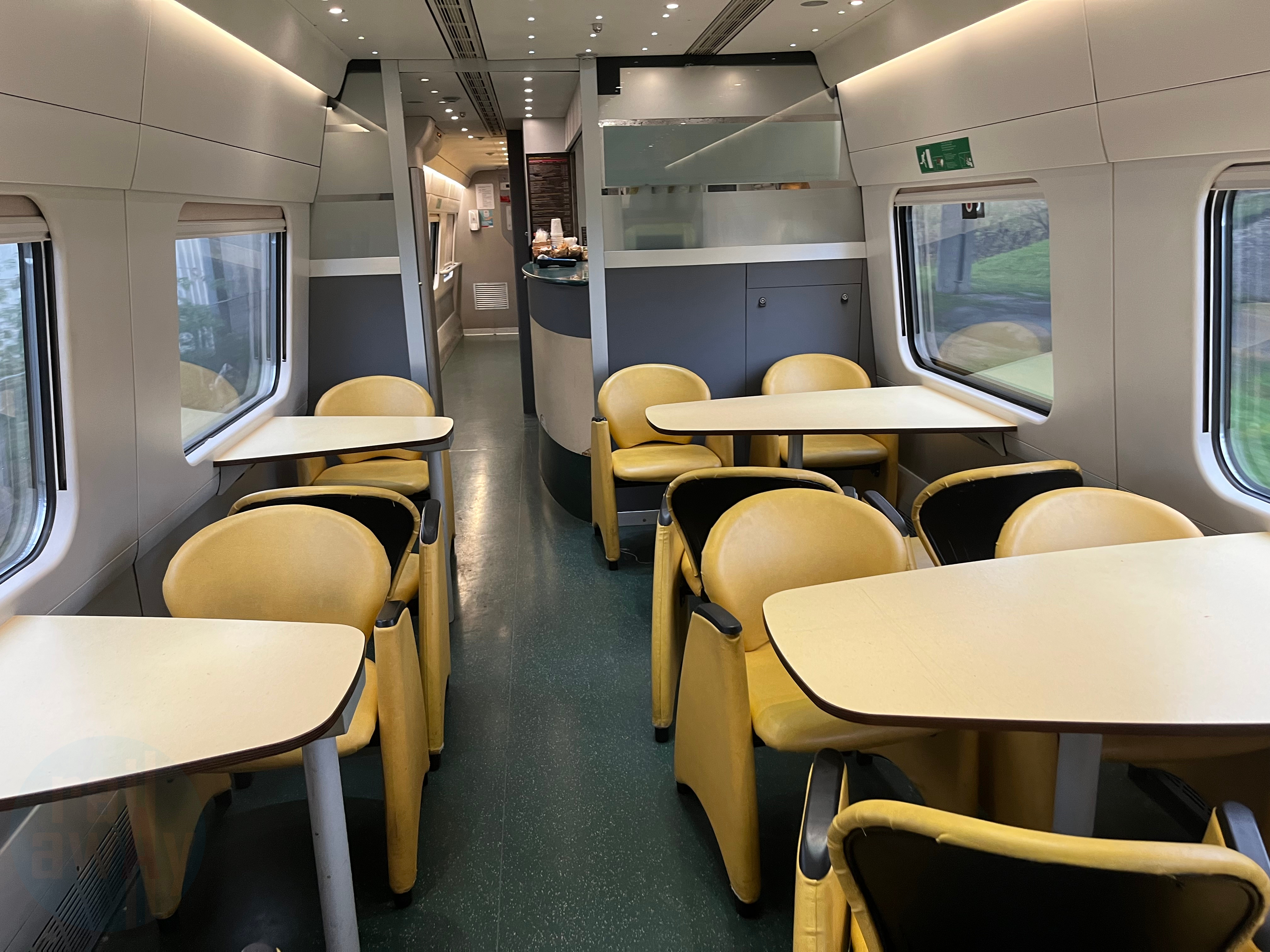 A bar area is in the centre of the car with yellow seats arranged in tables of 2 and 4
