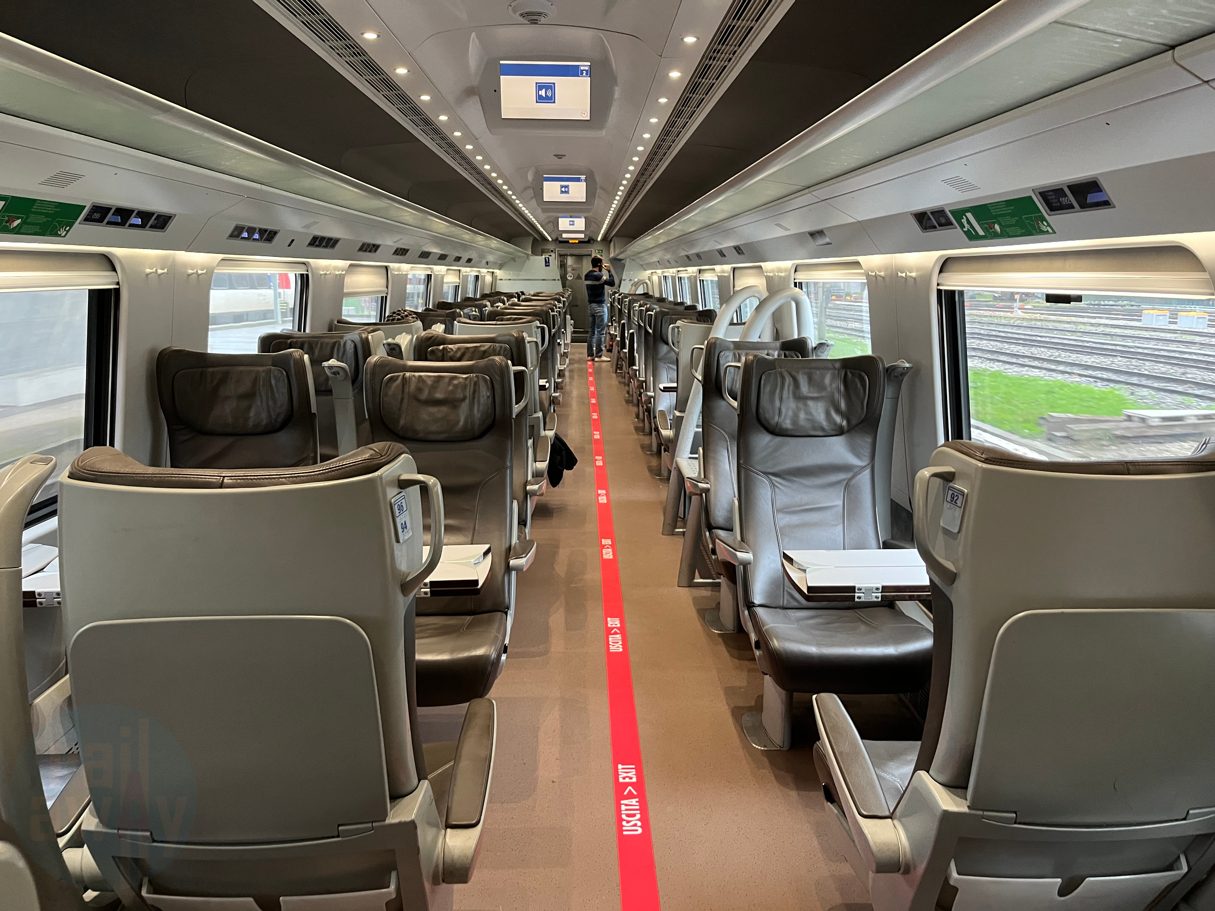 First Class seating in a 2+1 configuration. The chairs are in brown leather with foldable tables.