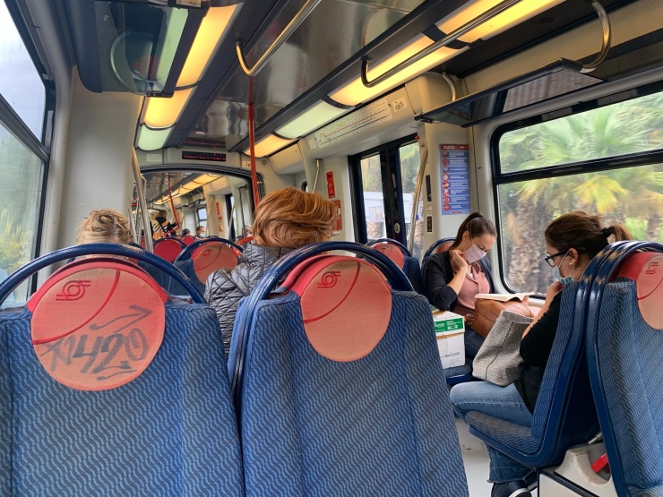 The interior of the ETR221 train with blue and red seats and passengers reading