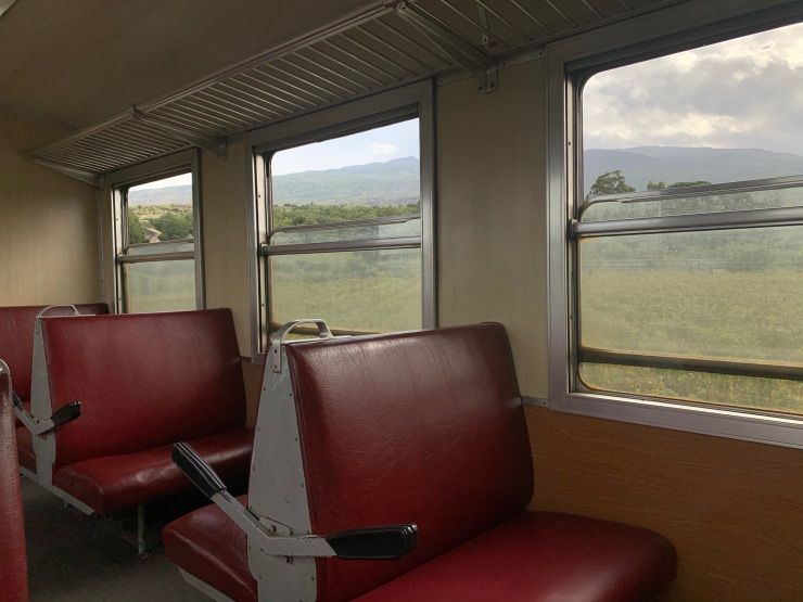 Onboard the Circumetnea with a view of the volcano in the background through the windows and red bench seats.