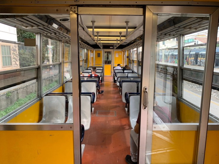 Interior picture of the train from Poggiomarino to Napoli Porta Nolana with hard plastic seats, yellow walls and red floors